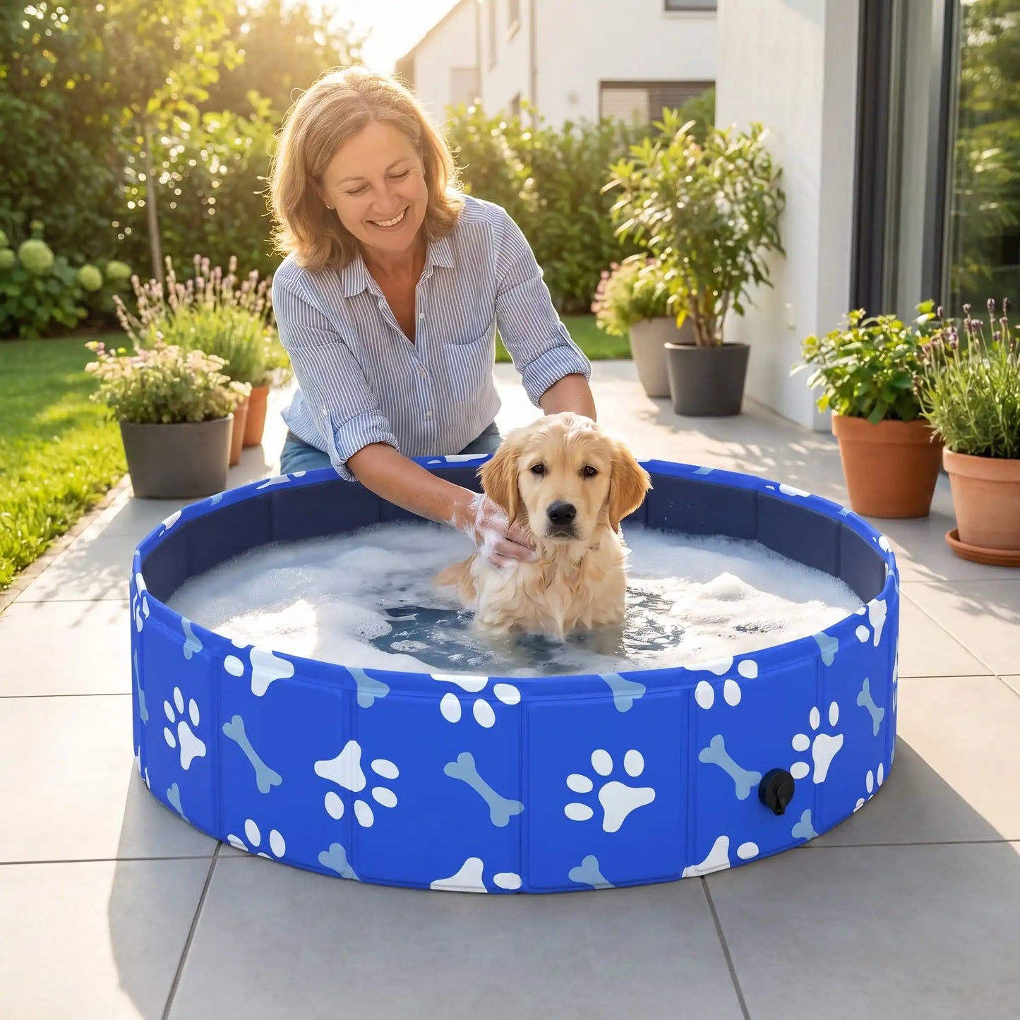 Piscine-rigide-pour-chien-rigide en panneaux MDF robuste anti-affaissement, pliable et lavable de diamètre 80 cm et de 20 cm de hauteur étudié pour une entrée et sortie facile et sécurisé pour le chien avec bouchon de vidange pratique et rapide, polyvalente piscine à balle, bassin, baignoire pour toilettage-un chiot qui se fait au toiletter dans sa piscine rigide pliable au design mignon de pattes et d'os blanc sur la terrasse de la maison en été