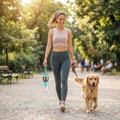 Bouteille-d-eau-pour-chien-chiot-550-ml avec compartiment pour friandises ou croquette amovible, bouton pour distribuer l'eau de manière hygiénique et contrôlé , bec adapté large et hygiénique sans BPA ni produits toxiques avec sangle de transport pour voyage, promenades, sorties en voiture-un maitresse sportive et souriante en balade avec son chien heureux et haletant qui porte par la sangle la bouteille d'eau distributrice d'eau et avec son réservoir de friandises remplies pour leur canicross