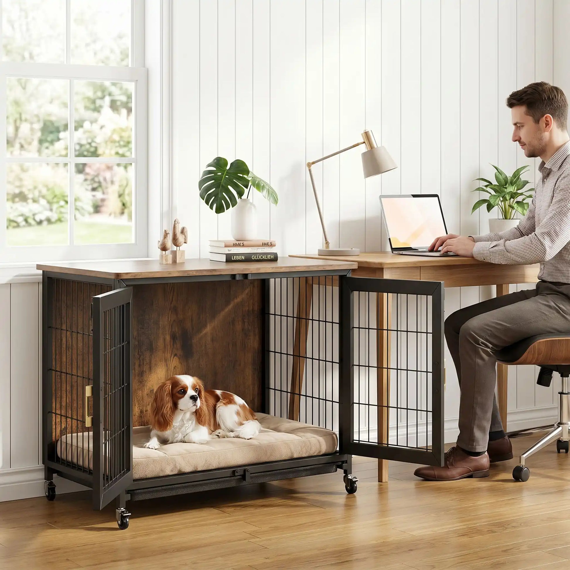 Cage-chien-interieur-avec-4-roues-mobiles rotative à 360° avec freins de sécurité, en bois et acier de couleur noir mat, meuble rectangulaire design moderne et épuré, double porte avant avec serrures robustes à point pour chien et chiot de petite à moyenne taille, de 0 à 30 kg maximum-un chien de moyenne taille couché confortablement sur son matelas dans le meuble cage interieur design bois et acier noir moderne, la double porte ouverte au pied du bureau de son maitre qui  travaille sur son ordinateur 