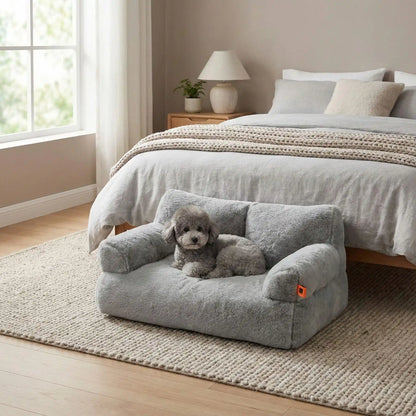 Canapé-petit-chien-douillet-anti-poils-déhoussable et lavable en machine-housse en peluche ultra-douce avec fond antidérapant et imperméable avec accoudoirs cylindrique dossier et assise au rembourrage 100% coton haute densité, ergonomique et 4 saisons, respirant et chaud-un caniche nain confortablement couché sur le canapé pour chien gris au toucher velours dans la chambre de la maison