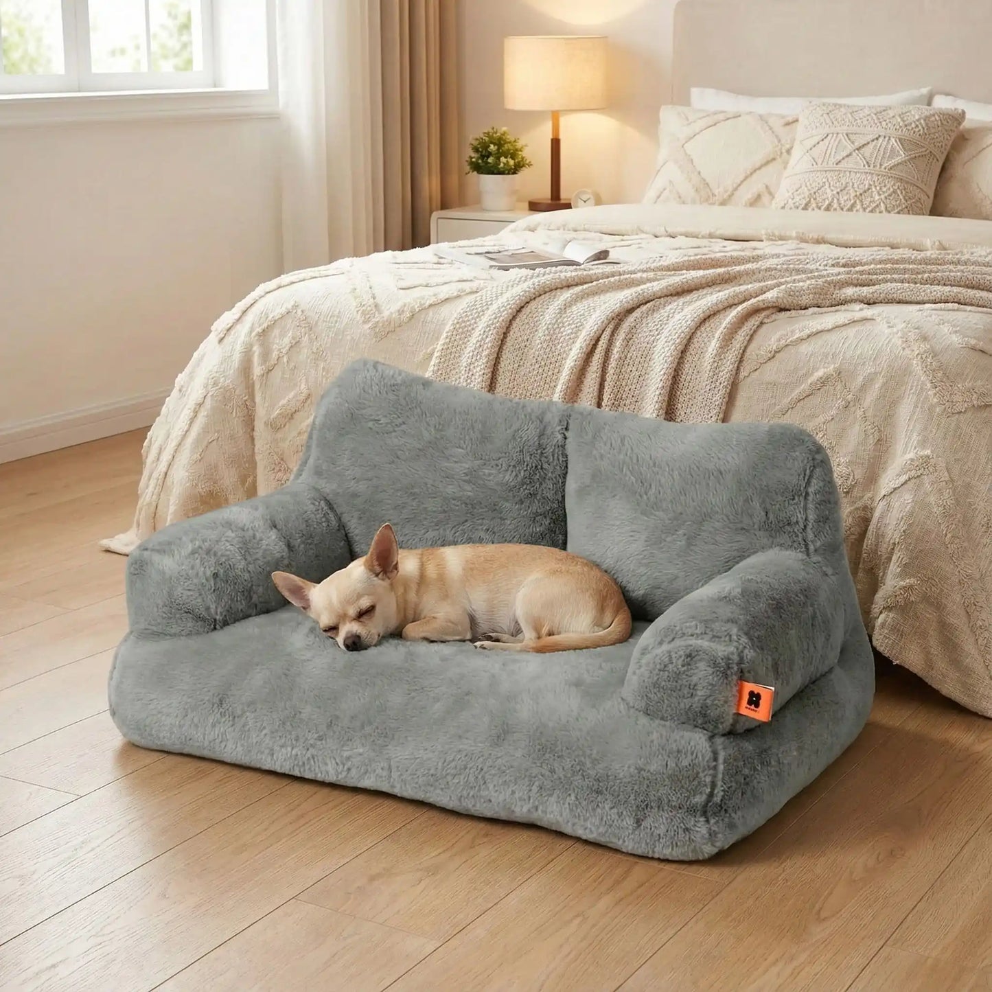Canapé-petit-chien-douillet-anti-poils-déhoussable et lavable en machine-housse en peluche ultra-douce avec fond antidérapant et imperméable avec accoudoirs cylindrique dossier et assise au rembourrage 100% coton haute densité, ergonomique et 4 saisons, respirant et chaud-un chien nain confortablement couché sur le canapé pour chien gris au toucher velours dans la chamlbre de l'appartement
