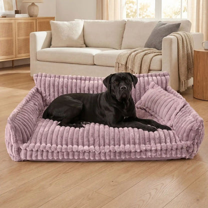 Canapé-pour-chien-chiot-déhoussable, lavable en machine, housse en velours douce comme un lit en peluche, avec accoudoirs et dossier entourant au rembourrage 100% coton PP avec un oreiller lavable en velours assorti pour chien de 0 à + de 45kg, antidérapant et fond imperméable-un grand chien couché confortablement avec son oreiller sur le grand canapé xxl de 120 cm de long en velours de couleur mauve qui  dans le salon de l'appartement