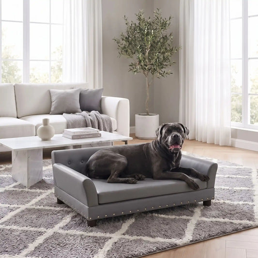 Canapé-pour-chien-xxl-120-cm-matelas orthopédique à mémoire de forme en coton PP épais déhoussable, 100% imperméable et résistant aux griffes en cuir PU sur 4 pieds en bois et structure robuste en bois d'eucalyptus robuste avec une capacité de charge de 100 kg pour chien de moyenne à grande taille de couleur gris foncé- un gros chien couché confortablement sur le canapé design en bois avec accoudoir et matelassé avec matelas amovible orthopédique déhoussable et lavable dans le salon de l'appartement