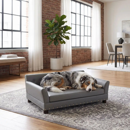 Canapé-pour-chien-xxl-120-cm-matelas orthopédique à mémoire de forme en coton PP épais déhoussable, 100% imperméable et résistant aux griffes en cuir PU sur 4 pieds en bois et structure robuste en bois d'eucalyptus robuste avec une capacité de charge de 100 kg pour chien de moyenne à grande taille de couleur gris foncé- un chien de race moyenne couché confortablement sur le canapé design en bois avec accoudoir et matelassé avec matelas amovible orthopédique déhoussable et lavable dans le salon 