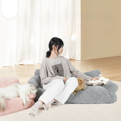 Canapés-pour-chiens-xxl-120-cm, déhoussable, antidérapant et lavable en machine, en peluche éponge douce et rembourrage 100% coton haute densité, housse 100% imperméable, avec 2 dossiers et 2 accoudoirs pour chien de 0 à +40 kg- une maitresse assise avec ses petits chiens sur le canapé xxl pour chien et chiot de grande race de couleur gris avec son chat allongé confortablement sur le canapé rose dans le salon de l'appartement