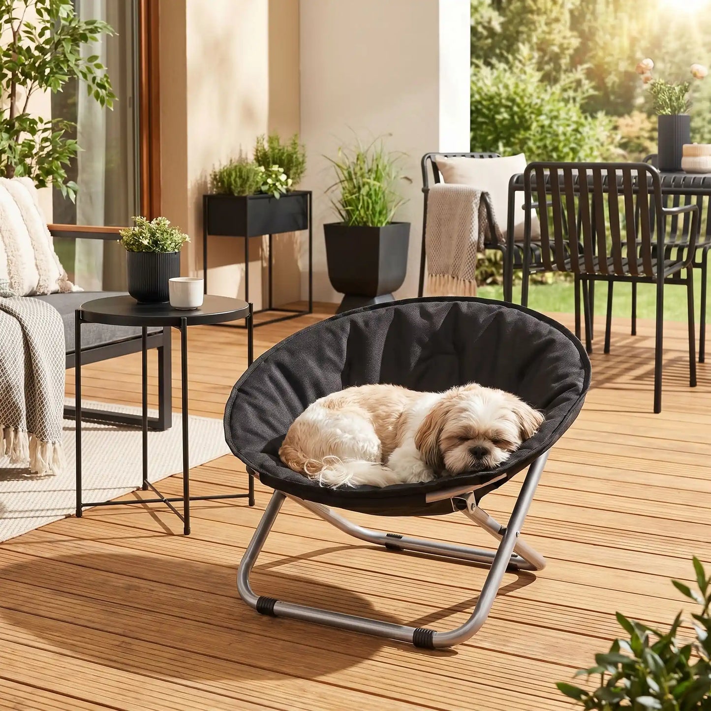 Chaise-pour-chien-chiot déhoussable et lavable, imperméable, structure design en acier robuste arrondie comme un cocon entourant avec deux hauteurs adaptables, pliable avec sa housse en nylon résistant aux griffes pour chiot et chien de 0 à 7 kilos-un Shih Tzu qui dort paisiblement dans sa chaise ronde noir sur la terrasse de la maison en été