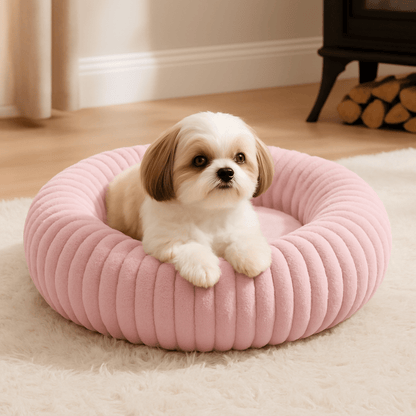 Coussin-anti-stress-chien-chiot-lavable en machine-rembourrage 100% coton haute densité-ergonomique-épais-antidérapant-housse ultra-douce en velours-résistant aux griffes-design-un chiot couché confortablement et heureux dans son lit rond avec rebord surélevé entourant et sécurisant anti-anxiété pour chien de petite taille de couleur rose sur le sol du salon de la maison