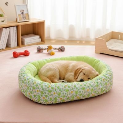 Coussin-anti-stress-chien-motif-floral-apaisant de forme ovale avec rebord surélevé à 360° pour un effet anti anxiété- ergonomique rembourrage et tissu 100% coton haute densité écologique et hypoallergénique-design pastel avec fleur délicates-lavable en machine et antidérapant pour chien de petite taille de 0 à 12 kilos-un chiot qui dort lové en boule contre le rebord rembourré du coussin en forme de beignet moelleux,chaud et respirant, matériau écoresponsable de couleur vert dans la bibliothèque 