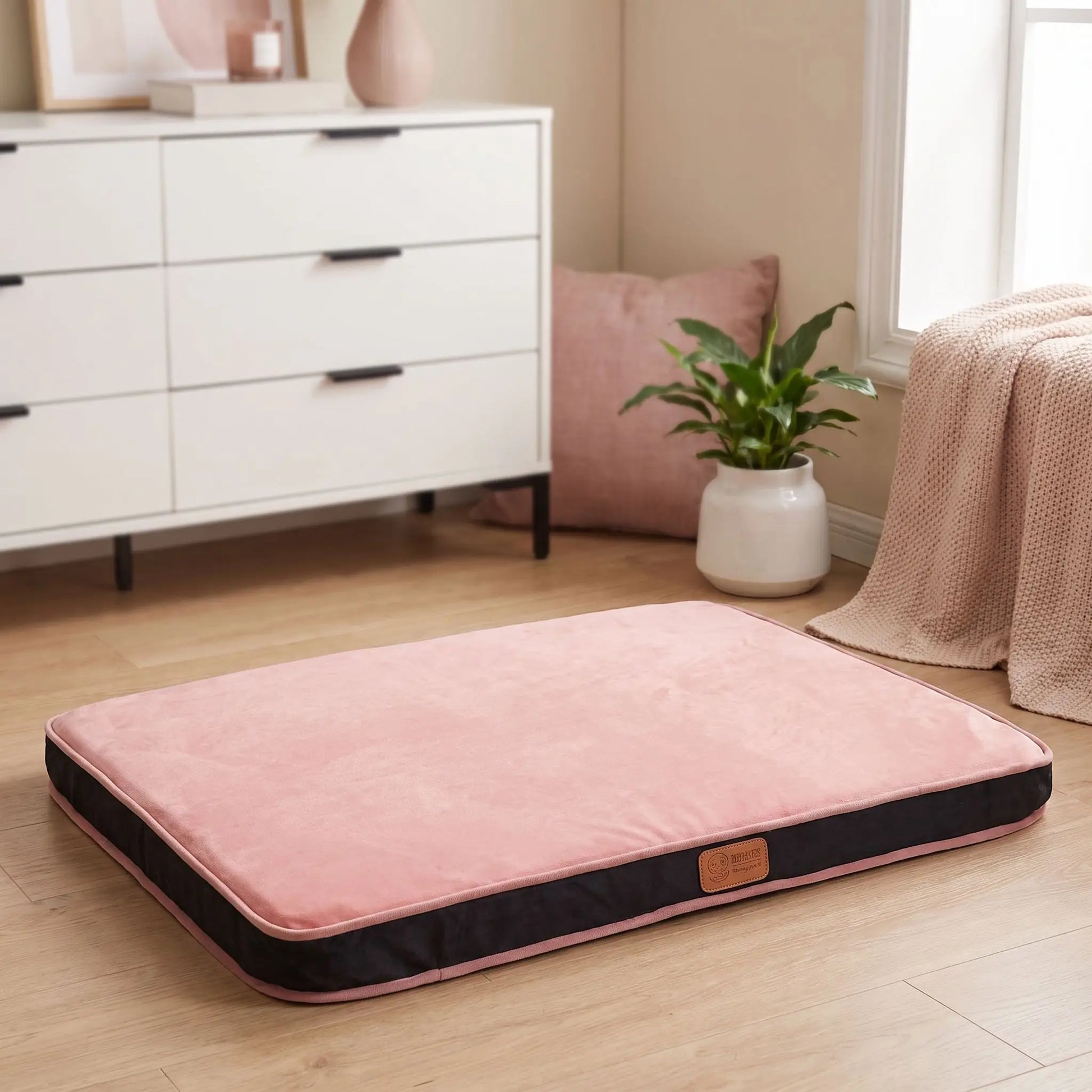 Coussin-déhoussable-chien-chiot-orthopédique avec son matelas en éponge coton haute densité anti-affaissement, rectangulaire et épais, housse en velours et solide, tapis d'appoint pour panier, cage, niche, etc. fond antidérapant, déhoussable et lavable en machine, disponible en 3 tailles S, M et L pour chien jusqu'à 20 kilos max-gros plan sur le coussin rectangulaire en velours de couleur rose sur le sol en parquet de la chambre de la maison