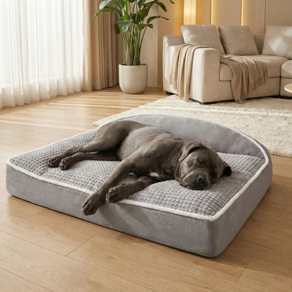 Coussin-pour-chien-xxl-matelas-à-mémoire-de-forme- avec-traversin en L rembourrage épais 100% coton haute densité ergonomique, imperméable antidérapant et déhoussable et lavable en machine pour chien de grande taille jusqu'à 50 kg max, résistant aux griffes et morsure- un  chien de grande race qui dort paisiblement et couché confortablement sur le flanc et de tout son long sur le lit rectangulaire de 120 cm de couleur marron et beige dans le salon de la maison
