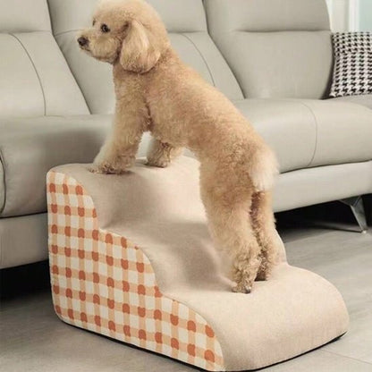 Escalier-mousse-pour_chien-chiot-antidérapant, déhoussable lavable en machine avec mousse haute résilience à mémoire de forme pour protèger les articulations sensibles, sécurisé , confortable, résistant aux griffes pour petit et chien de moyenne taille-design velours sur le dessus ultra-doux et tissu en coton solide avec motif orange à carreaux style vichy-un petit chien qui monte confortablement sur l'escalier de 3 marches en mousse pour monter sur le canapé du salon en toute sécurité