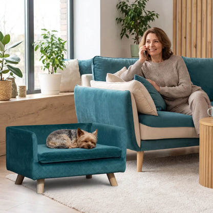 Fauteuil-pour-petit-chien-chiot-cocon- de petite taille de 0 à 8 kilos, structure en bois avec 4 pieds de bouleau robuste, dossier et accoudoir en U design nordique , 100 coton, toucher velours quadrillé pour un effet chic, matelas d'assise rectangulaire amovible en mousse 100% coton haute densité ergonomqiue déhoussable et lavable en machine, imperméable et résistant aux griffes-un chien de race toy qui dort couché confortablement sur son petit fauteuil design de couleur bleu canard surélevé dans le salon 