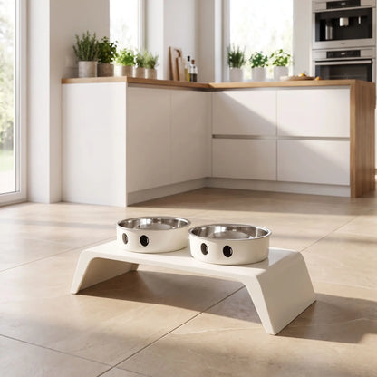 Gamelle-chien-surélevée-chiot-design de couleur blanc épuré de 8,5 cm de hauteur avec ses deux gamelles en inox amovibles lavable en lave-vaisselle avec pieds antidérapants, adapté aux chiots et chiens de petite race ou petite taille- gros plan sur la station d'alimentation avec son support design moderne blanc et ses deux gamelles en inox sur le support blanc en ABS aux formes épurés  et moderne sur le sol de la cuisine lifestyle de la maison
