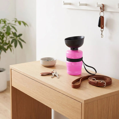 Gourde-pour-chien- et chiot bouteille-d-eau-500-ml sans BPA , ABS de qualité alimentaire avec bol intégré en silicone repliable, compact, valve de sécurité anti fuite, et sa sangle de transport-gros plan sur la gourde pour chien de couleur rose avec sa sangle noir solide pour un tranqport facile posé sur la console de l'entrée à côté de la laisse du chien et des clefs de ses maitres 