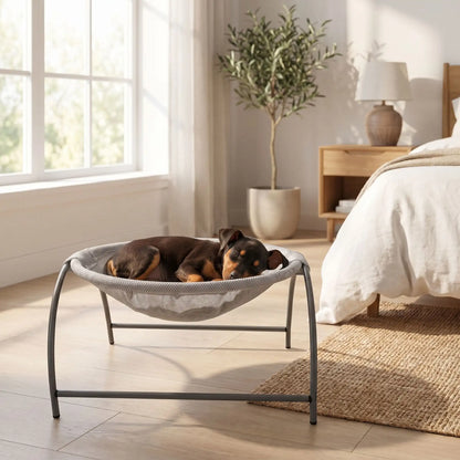 Hamac-pour-chien-chiot-exterieur et interieur en maille respirante et hypoallergénique, structure solide en acier avec 3 pieds et renfort par de barres latérales, cerceau central entourant et apaisant pour les chiot et chien de petite taille et de races naines de 0 à 3 kilos max , imperméable et lavable-un chiot chien de taille naine qui dort paisiblement niché dans son hamac rond gris entourant avec sa structure en acier sur pieds dans la chambre de l'appartement en été