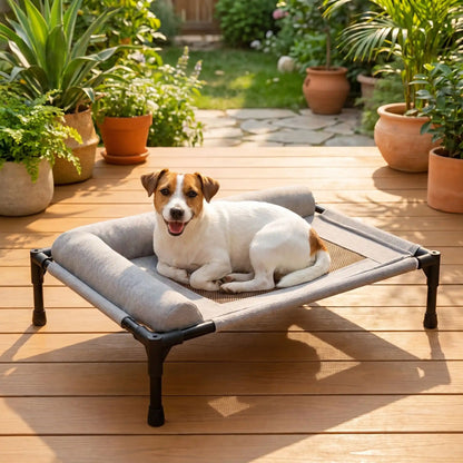 Lit-de-camp-chien-chiot-confort avec 2 traversins cylindriques en L au rembourrage 100% coton haute densité pour un soutien ergonomique pour sa tête ou son cou, entourant et sécurisant avec tissu en maille teslin ultra-résistante en teslin et contour en tissu oxford imperméable sur une structure en acier et coin arrondis en plastique sécurisé et pieds anti rayure et antidérapant-un Jack russell heureux couché sur son lit hamac surelevé de couleur gris  sur la terrasse de en bois de la maison en été