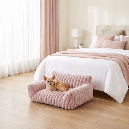 Mini-canapé-chien-chiot-déhoussable, lavable en machine ,coton, housse en peluche douce au toucher velours, rembourrage ergonomique en mousse à mémoire de forme pour un soutien optimal, disponible en  couleurs blanc et rose et 3 tailles S, M et L pour chiot et chien de petite taille de 0 à 10 iols max-un chien de race toy couché confortablement niché contre le dossier haut et l'accoudoir rembourré du mini fauteuil pour chien de couleur rose dans la chambre de la maison