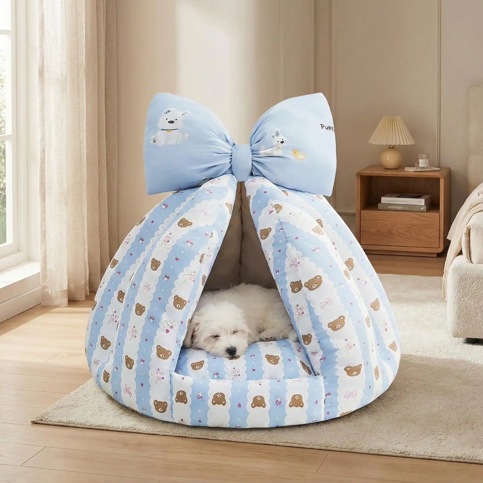 Niche-chien-interieur-coussin-apaisant-rembourrage et tissu 100% coton PP hypoallergénique et écoresponsable poiur petit chien et chiot de 0 à 8 kilos-coussin amovible et lavable en machine, antidérapant et fond imperméable-deux coloris disponible bleu et beige avec noeud décoratif sur le sommet-un Coiton de Tuléar qui dort paisiblement au chaud dans sa niche en forme de tipi chaud et respirant sur le sol de la chambre de la maison