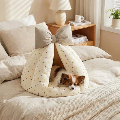 Niche-chien-interieur-coussin-apaisant-rembourrage et tissu 100% coton PP hypoallergénique et écoresponsable poiur petit chien et chiot de 0 à 8 kilos-coussin amovible et lavable en machine, antidérapant et fond imperméable-deux coloris disponible bleu et beige avec noeud décoratif sur le sommet-un chien de race naine qui dort paisiblement dans sa niche en forme de dôme chaud et respirant sur le lit de la chambre de l'appartement