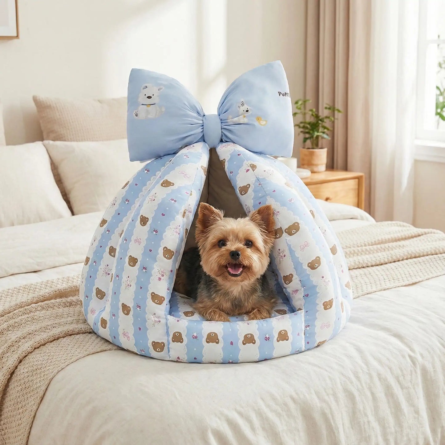 Niche-chien-interieur-coussin-apaisant-rembourrage et tissu 100% coton PP hypoallergénique et écoresponsable poiur petit chien et chiot de 0 à 8 kilos-coussin amovible et lavable en machine, antidérapant et fond imperméable-deux coloris disponible bleu et beige avec noeud décoratif sur le sommet-un chien de race Tpy couché et heureux dans sa niche en forme de dôme chaud et respirant sur le lit de la chambre de son maitre