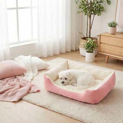 Panier-chien-lavable-chiot-design avec motif os, lavable en machien antidérapant avec rebord, coussin moelleux et ergonomique au rembourrage 100% coton haute densité de forme rectangulaire pour chien de petite à moyenne taille de 0 à 18 kilos max- un bichon maltais qui se repose confortablement dans son panier épais, chaud, hypoallergénique et ultra doux de couleur blanc et rose dans le salon de l'appartement