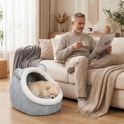 Panier-chien-chiot-niche-anti-stress, conception semie fermée avec toit et coussin amovible en velours rembourrage 100% coton PP, niche en peluche douce et design mignon avec oreilles d'ours, fond antidérapant et imperméable, lavable en machine pour chiot et chien de petite race de 0 à 3 kg-un chien de race Toy qui dort couché confortablement dans son panier avec toit en dôme comme une cabane en peluche douce au pied de son maitre qui boit son café assis sur le canapé du salon de la maison