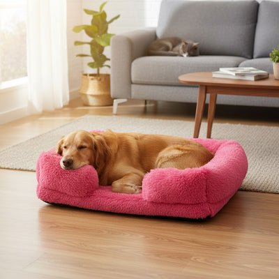 Panier-chien-xxl-déhoussable-orthopédique-coussin rectangulaire avec rebord surélevé en traversin qui sert d'oreiller ergonomique à 360° rembourrage 100% coton haute densité pour un effet anti stress et anti anxiété-housse en peluche ultra douce, hypoallergénique, imperméable, antidérapant et lavable en machine pour chiot et chien de taille moyenne à grande jusqu'à 45 kg max-un chien de grande taille qui dort paisiblement dans son coussin rectangulaire de couleur rose dans le salon de la maison