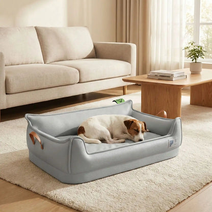 Panier-orthopedique-chien-simili-cuir-imperméable, déhoussable, antidérapant et lavable avec deux poignée de transport, ne retient pas les poils, avec dossier et rebord surélevé, résistant aux griffes en cuir végan et matelas haute résilience à mémoire de forme en coton PP, design moderne et soigné avec coutures solides pour chiot et chien de petite à moyenne taille-un Jack Russell qui dort paisiblement dans son  panier design et moderne de couleur gris dans le salon de l'appartement