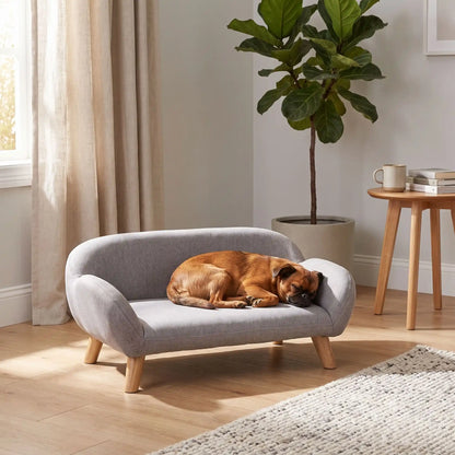 Petit-canape-pour-chien-chiot-design de couleur gris, dossier et accoudoirs arrondis dans un style scandinave, tissu résistant aux griffes, rembourrage 100% coton haute densité pour un confort optimal, structure en bois massif et surélevé avec 4 pieds en bois massif pour chiot et chien de 0 à 8 kilos-un chien de race  miniature qui dort couché confortablement en boule sur son canapé gris design sur pied en bois massif et rembourrage en éponge coton ergonomique dans la chambre de la maison