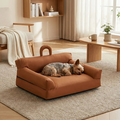 Petit-canapé-pour-chien-chiot-imperméable, déhoussable lavable en machine, en Cuir végan et rembourrage 100% coton haute densité et résilience, avec accoudoirs, dossier et assise ergonomique, avec poignée de transport, antidérapant et anti humidité, durable solide et résistant aux griffes pour chiot, petit chien et race naine de 0 à 10 kilos- un Yorkshire qui dort paisiblement blotti dans son mini canapé marron style vintage chic dans le salon de l'appartement