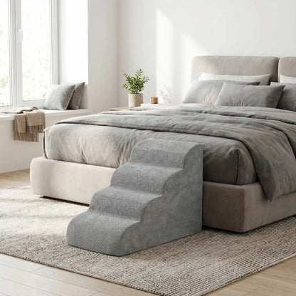 Petit-escalier-pour-chien-dehoussable-en-mousse haute résilience qui atténue la pressions sur  ses articulations, résistant et doux pour ses coussinets, déhoussable, imperméable et lavable en machine de couleur gris pour chien de petite taille, polyvalent compact et transportable-un escalier gris placé contre le lit du propriétaire du chien dans la chmabre de la maison