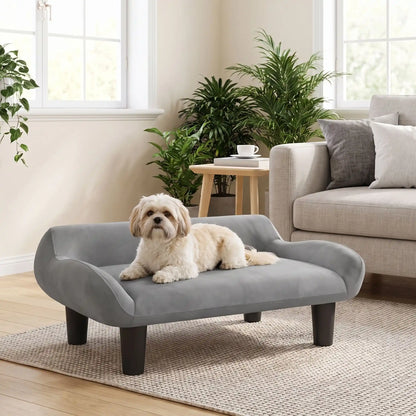 Petit-fauteuil-pour-chien-chiot-design de couleur gris, dossier et accoudoirs arrondis dans un style scandinave, velours résistant aux griffes,rembourrage 100% coton haute densité pour un confort optimal,structure en bois massif et surélevé avec 4 pieds en bois massif pour chiot et chien de 0 à 8 kilos-un chien de petite taille couché confortablement sur son canapé gris design sur pied en bois massif et rembourrage en éponge coton ergonomique dans le salon de la maison