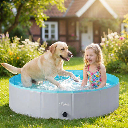 Piscine-pour-chien-xxl-chiot-rigide-bouchon-vidange rapide et facile,pliable et transportable en panneaux de fibres rigides et naturels avec PVC ultra-résistant avec couche intérieure renforcée de diamètre 160 cm pour chien de grande race, fond antidérapant et résistant aux griffes-un chien de grande race qui joue tout heureux avec une petite fille qui rit dans la grande piscine pour chien rigide sur la terrasse du jardin de la maison en été
