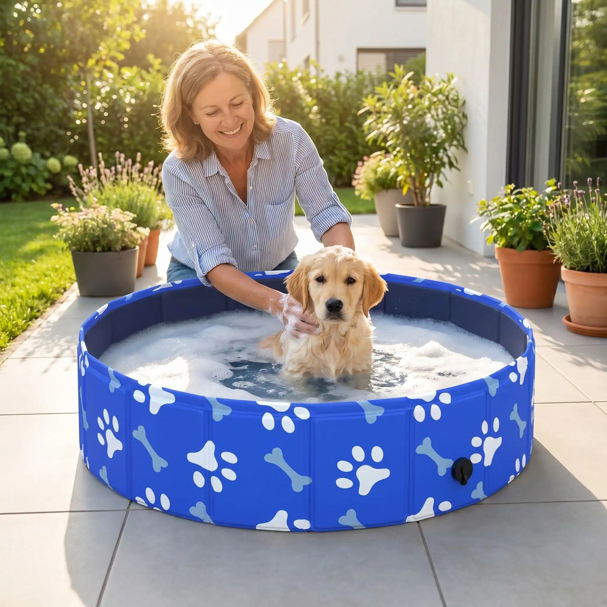 Piscine-rigide-pour-chien-rigide en panneaux MDF robuste anti-affaissement, pliable et lavable de diamètre 80 cm et de 20 cm de hauteur étudié pour une entrée et sortie facile et sécurisé pour le chien avec bouchon de vidange pratique et rapide, polyvalente piscine à balle, bassin, baignoire pour toilettage-un chiot qui se fait au toiletter dans sa piscine rigide pliable au design mignon de pattes et d'os blanc sur la terrasse de la maison en été