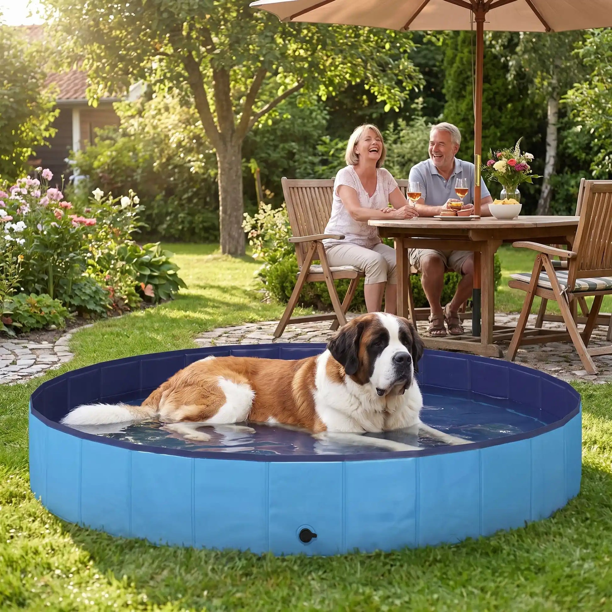 Piscine-pour-grand-chien-rigide-xxl, panneaux MDF robuste anti-affaissement, pliable et lavable de diamètre 200 cm et de 30 cm de hauteur étudiée pour une entrée et sortie facile et sécurisé pour le chien avec bouchon de vidange pratique et rapide, polyvalente piscine à balle, bassin, baignoire pour toilettage-un chien de très grande taille qui se rafraichit pour supporter la chaleur dans sa grande piscine robuste sous le regard amusés de ses maitres qui boivent l'apéritif dans le jardin de la maison en été
