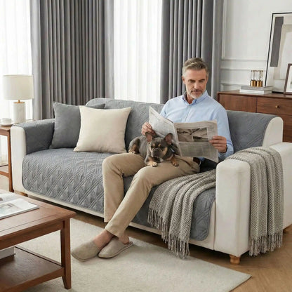 Protection-canape-chien-couverture-protege-siege-imperméable, résistant aux griffes, durable, tapis ou couverture qui protège des accidents, humidité saleté, boue,tissu anti poils, lavable en machine en 3 tailles M, L et XL pour canapé de 1/2/3 places, futon, canapé relax et canapé avec angles ou méridienne-un maitre qui lit son journal  assis avec son petit chien sur les genoux  sur le protege canape de couleur gris au rembourrage 100% coton sur le canapé du salon de la maison