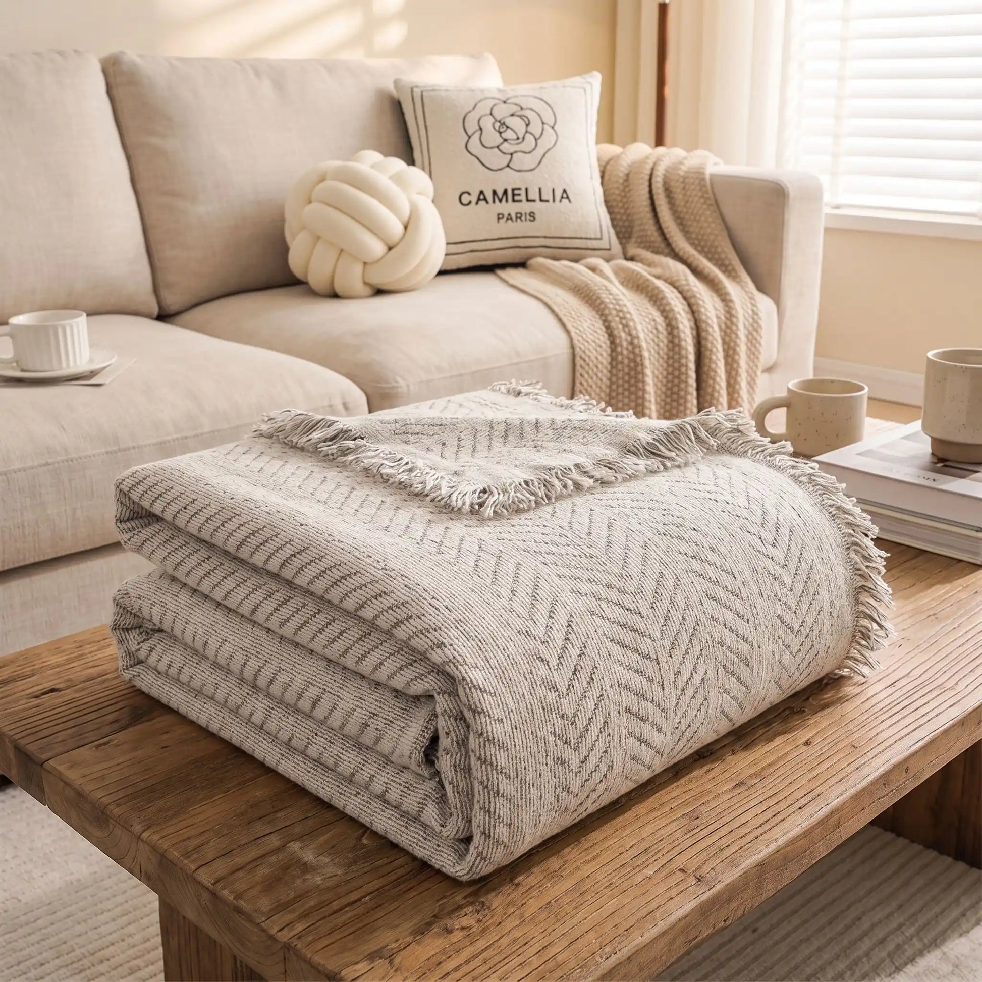 Protection-canape-chien-anti-poils-résistante aux griffes, tissage chenille coton et polyester, écoresponsable avec franges pour un style bohème chic de couleur gris clair, dispoinble en 4 tailles pour fauteuil/canapé une place, deux places, 3 places et 4 places, lavable en machine, doux respirant confortable et 4 saisons-gros plan sur le plaid de protection plié disponible en 4 tailles pour s'adapter à tous mobilier, légère, transportable, idéal pour les déplacement et protéger les sièges voiture 