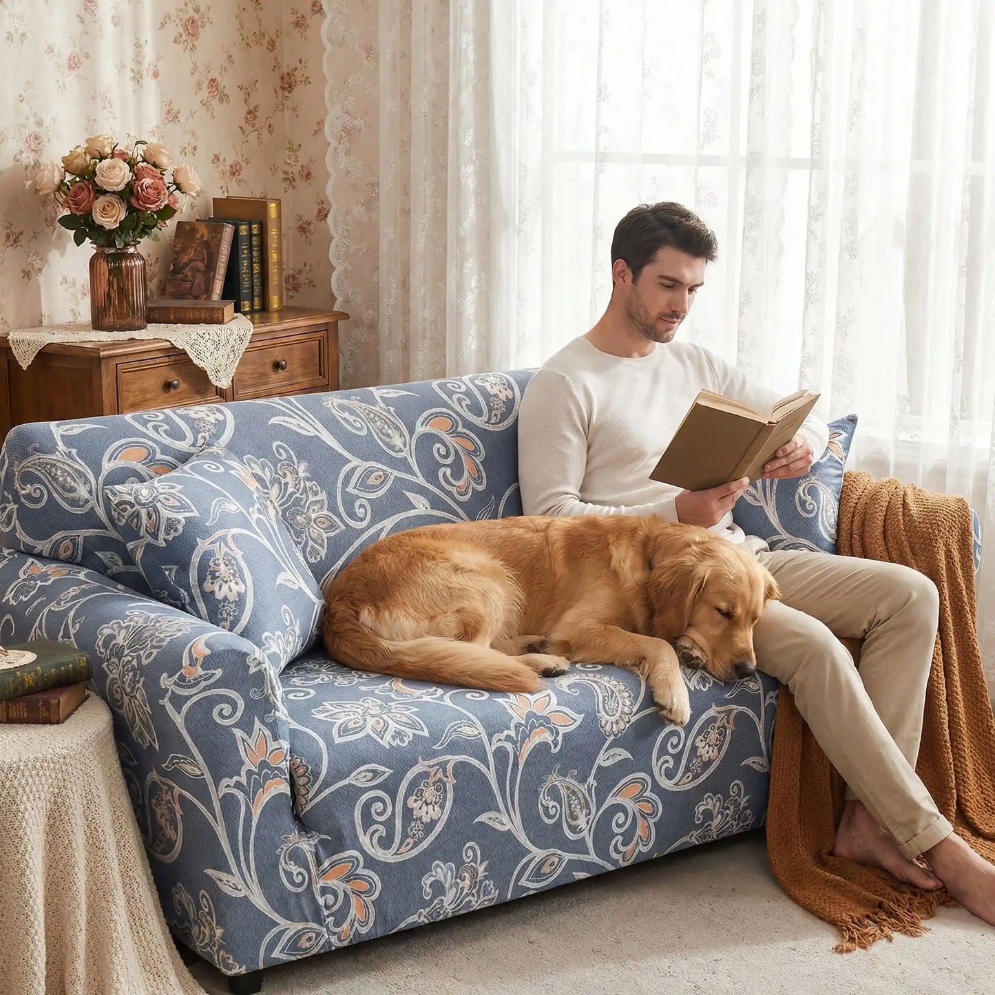 Protection-canape-chien-anti-poils-anti accident, lavable en machine, haute élasticité et resistante aux griffes et à l'usure, universelle en 4 tailles pour fauteuil, canapé de 2/3/4 places, avec élastique et bloque plis- design floral délicat- un maitre qui lit son livre assis confortablement sur le canapé qui à côté son grand chien couchésur le canapé avec sa housse de style anglaise dans le salon de l'appartement