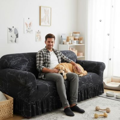 Protection-canape-chien-anti-poils-anti accident, lavable en machine, haute élasticité et resistante aux griffes et à l'usure, universelle en 4 tailles pour fauteuil, canapé de 2/3/4 places, avec élastique et bloque plis- design floral délicat- un homme qui caresse son chien couché sur sa jambe, tout deux  confortablement installés sur le canapé avec sa housse extensible universelle noir dans le salon de l'appartement