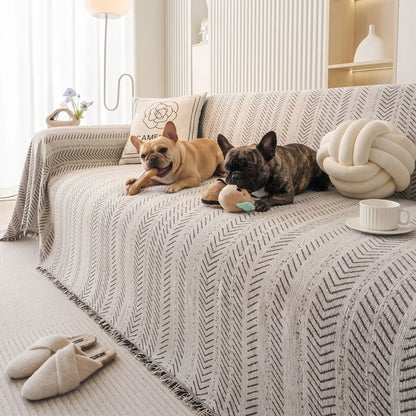 Protège-canapé-pour-chien-plaid-anti-poils-résistante aux griffes, tissage chenille coton et polyester, écoresponsable avec franges pour un style bohème chic de couleur blanc et noir disponible en 4 tailles pour fauteuil/canapé une place, deux places, 3 places et 4 places, lavable en machine, doux respirant confortable et 4 saisons-deux chiens de races moyenne qui mâchent leur jouet de mastication en toute sécurité sur le plaid au design noir et blanc souple sur le canapé du salon de la maison