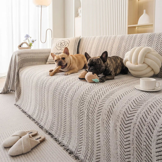 Protège-canapé-pour-chien-plaid-anti-poils-résistante aux griffes, tissage chenille coton et polyester, écoresponsable avec franges pour un style bohème chic de couleur blanc et noir disponible en 4 tailles pour fauteuil/canapé une place, deux places, 3 places et 4 places, lavable en machine, doux respirant confortable et 4 saisons-deux chiens de races moyenne qui mâchent leur jouet de mastication en toute sécurité sur le plaid au design noir et blanc souple sur le canapé du salon de la maison