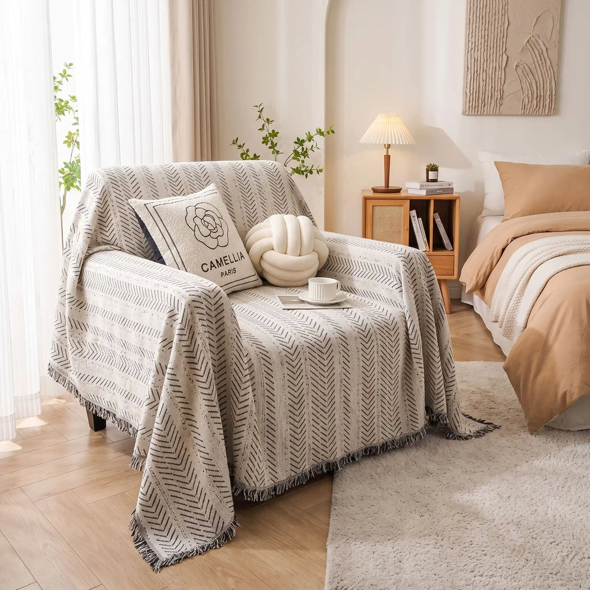 Protège-canapé-pour-chien-plaid-anti-poils-résistante aux griffes, tissage chenille coton et polyester, écoresponsable avec franges pour un style bohème chic de couleur blanc et noir disponible en 4 tailles pour fauteuil/canapé une place, deux places, 3 places et 4 places, lavable en machine, doux respirant confortable et 4 saisons-gros plan sur le plaid souple et resistant avec petites franches pour un design bohême chic blanc et touches discrètes de noir sur le fauteuil une place dans la chambre 