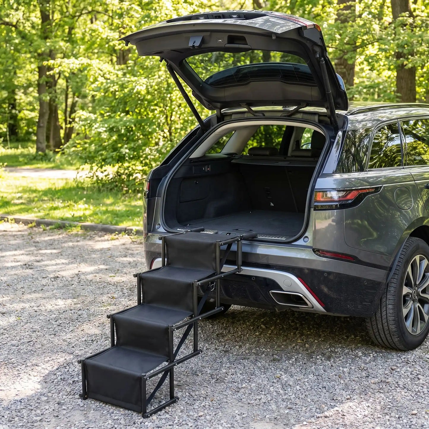 Rampe-escalier-pour-chien-chiot-pliable-voiture en acier oxydable et tissu oxford résistant aux griffes, antidérapant et 100% imperméable, pliage en accordéon, ouverture rapide et facile en un geste, poignées en mousse anti-rayures, légère avec sangles de transport de 4 marches avec hauteurs modulables 56 à 76 cm pour chien de moyenne à grande taille de 30 à 75 kilos max-gros plan sur la rampe escalier de 4 marches dépliables de couleur noir contre le coffre de la voiture pour un accès facile pour les chien
