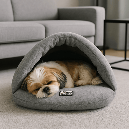 Sac-de-couchage-pour-chien-rembourrage 100 % coton haute densité, ergonomique, chaud et enveloppant, en forme de niche souple avec toit, polaire chaud, léger et transportable pour un effet apaisant et anti-stress pour chiot et chien de petite taille de 0 à 10 kg-un chien de petite taille qui dort paisiblement au chaud dans son sac de couchage gris dans le salon, isolé du froid du sol de la maison