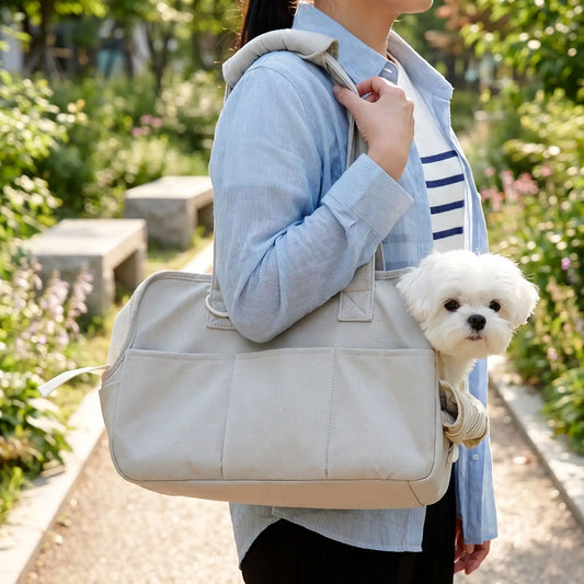 Sac-de-transport-chien-chiot- design sac à main avec multiples poches pour chien de 0 à 6 kg max,imperméable, coussins intérieur 100% coton lavable et rembourré, deux sangles avec poignées confort rembourré et renforcé pour être porté à la main ou sur l'épaule, attache laisse intégré pour sa sécurité et fillet refermable sur le so et ouverture latéral pour qu'il passe sa tête-gros plan sur le sac de transport où un petit chien regarde par l'ouverture en sécurité porté à l'épaule par sa maitresse en balade