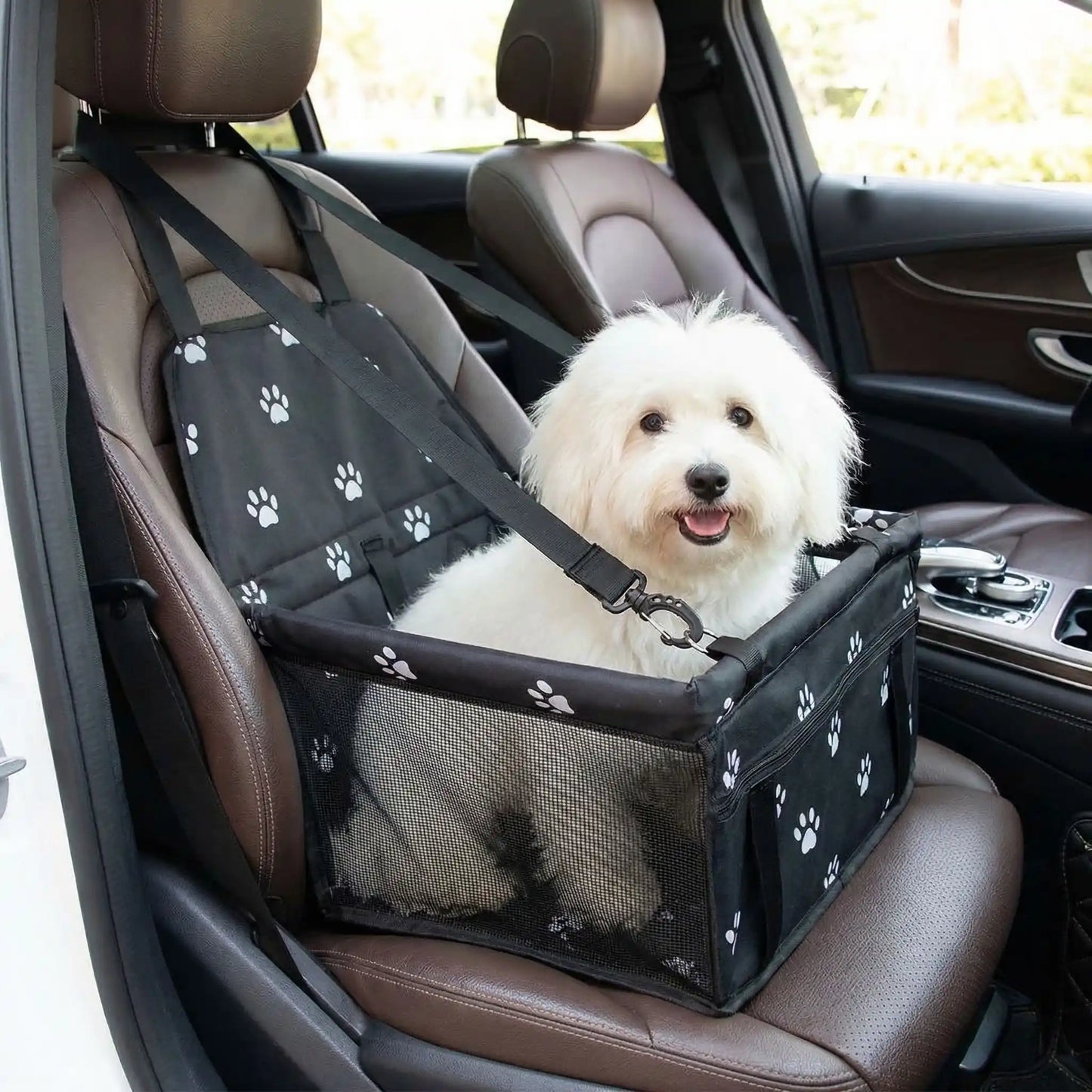 Siege-auto-chien-chiot, 100% imperméable et résistant aux griffes démontable et montage en quelques seconde avec attache ceinture de sécurité intégrée, sangles d'attaches solides et  faciles pour l'appuie tête pour chien de petite taille jusqu'à 8 kilos max-un coton de tuléar confortablement assis dans son siège auto noir avec motif de pattes de chien de couleur blanches sur le siège avant  passager à côté du conducteur