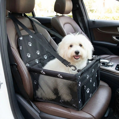 Siege-auto-chien-chiot, 100% imperméable et résistant aux griffes démontable et montage en quelques seconde avec attache ceinture de sécurité intégrée, sangles d'attaches solides et  faciles pour l'appuie tête pour chien de petite taille jusqu'à 8 kilos max-un coton de tuléar confortablement assis dans son siège auto noir avec motif de pattes de chien de couleur blanches sur le siège avant  passager à côté du conducteur
