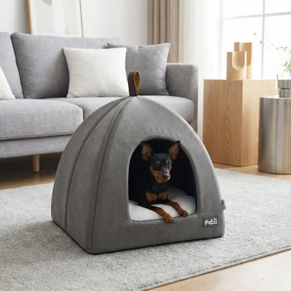 Tente-pour-chien-pliable avec poignée de transport, résistante compacte et légère, niche pour petits chien de race miniature ou toy de 0 à 3 kilos avec un coussin amovible et lavable en machine à laver, antidérapant et imperméable de couleur gris-un Pinscher nain couché confortablement dans sa niche intérieur sur le coussin rembourré 100% coton de haute densité dans le salon de l'appartement