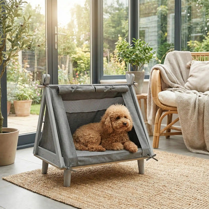 Tente-pour-chien-chiot-surélevé-bois naturel et tissu oxford 300D ultra-résistant et 100% imperméable avec une partie moustiquaire pour une circulation d'air optimale-un lit pour chiot et petit chien de 0 à 5 kilos solide et design écoresponsable avec son matelas ergonomique à mémoire de forme en éponge haute résilience 100% coton PP-un caniche nain couché confortablement dans sa tente avec matelas déhoussable et lavable en machine de couleur gris dans le salon