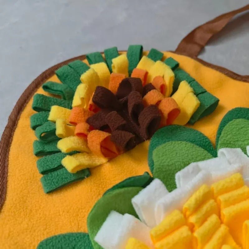 Tapis-de-fouille-chien-chiot, avec 6 compartiments de cachettes différentes, jouet intelligent pour chien et d'occupation pour un entrainement cognitif optimal, couleurs vives pour des contraste visible pour le chien, avec un pouet sonore, en feutre doux lavable en machine à 30° et antidérapant-gros plan sur un angle du tapis de fouille avec une cachette qui imite les herbes de la nature avec poignée pour le rangement 